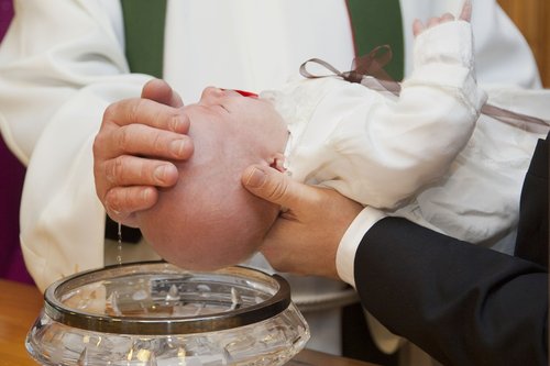 Ett barn blir döpt av en präst.