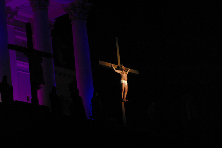 En mörk bild med ett ljus riktat på Kristus hängande på korset.